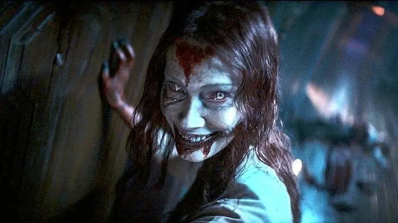 Evil Dead Rise's Ellie smiling bloodily in hallway