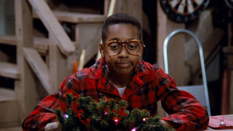 Steve Urkel sentado em frente a uma coroa de natal que parece