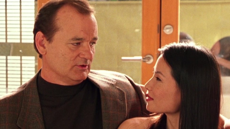 Bill Murray as John Bosley and Lucy Liu as Alex Munday sitting on a couch together in 2000's Charlie's Angels