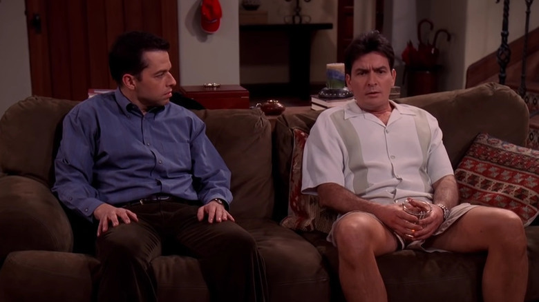 Charlie Sheen as Charlie Harper and Jon Cryer as Alan Harper sitting together on a couch in Two and a Half Men