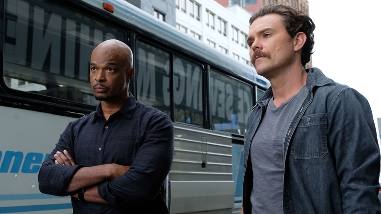 Damon Wayans and Clayne Crawford as Roger Murtagh and Martin Riggs, standing by a bus facing in the Lethal Weapon TV series