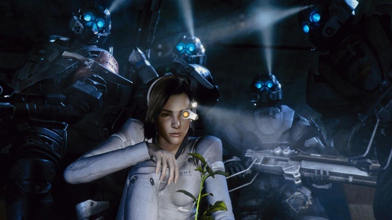 A woman peers at a plant as men in robotic suits and guns stand behind her