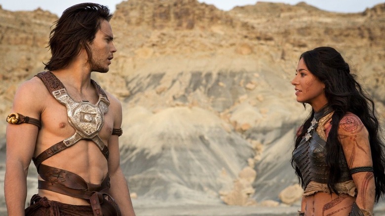 A bare chested man stares at a woman in armor
