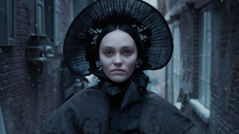 Lily-Rose Depp's Ellen is dressed in black on a snowy street in Nosferatu