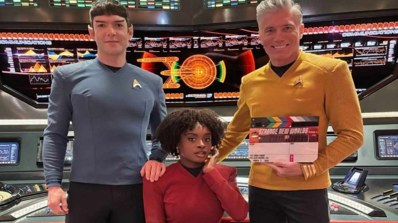 A production photo of Ethan Peck, Celia Rose Gooding, and Anson Mount, in costume as Spock, Uhura, and Pike, on the set of Star Trek: Strange New Worlds.