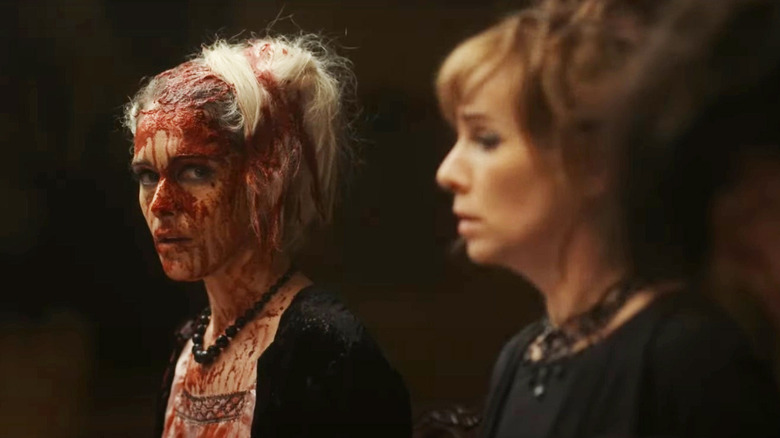 ariane lebed covered in red liquid looking at the camera and sitting next to a distressed fatma mohamed in the movie flux gourmet