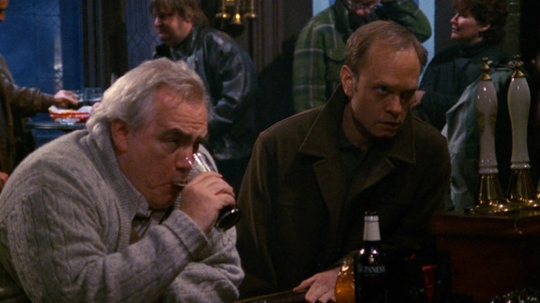 Brian Cox as Harry Moon drinking a pint next to David Hyde Pierce as Niles Crane seated at a bar in Frasier