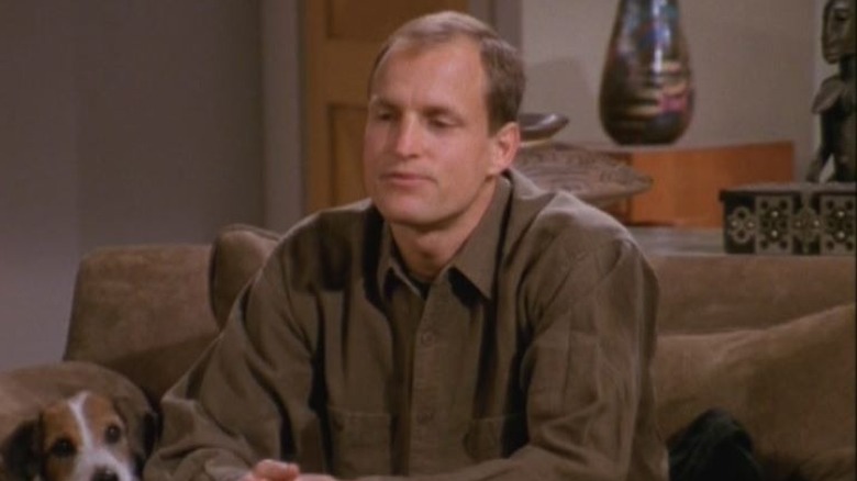 Woody Harrelson as Woody Boyd seated on a couch next to Moose as Eddie the dog in Frasier