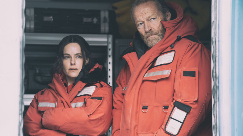 Emily Hampshire's Rose and Iain Glen's Magnus staring out of a doorway in The Rig