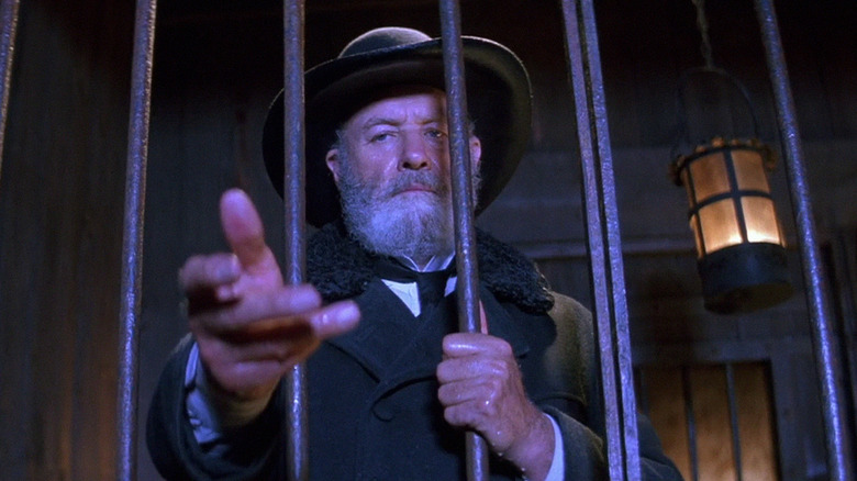 Gene Hackman reaches into a jail cell as Nicholas Porter Earp in Wyatt Earp