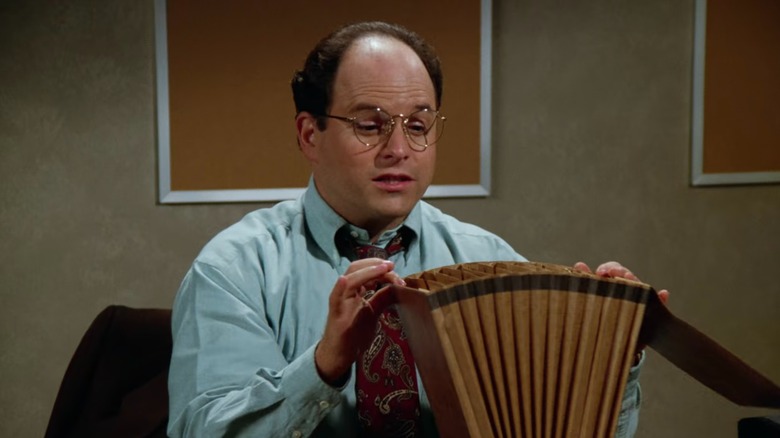 Jason Alexander's George peers into an accordion file in Seinfeld