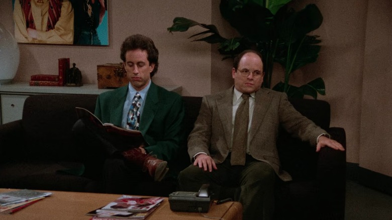 Jerry Seinfeld's Jerry reads a magazine and Jason Alexander's George looks nervous as they sit in a waiting room on Seinfeld