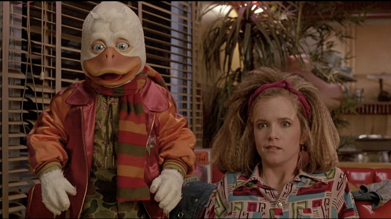 Howard the Duck and Lea Thompson as Beverly in a booth looking shocked in Howard the Duck