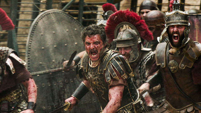 Pedro Pascal as General Acacius, covered in battle, charges into a fight in Gladiator II