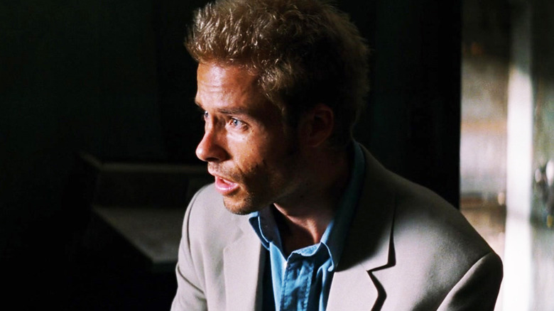 Guy Pearce's Leonard Shelby looks shocked as he stands in a dark room in Memento