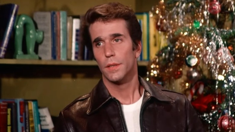 Henry Winkler's Fonzie stands in front of a Christmas tree in Happy Days