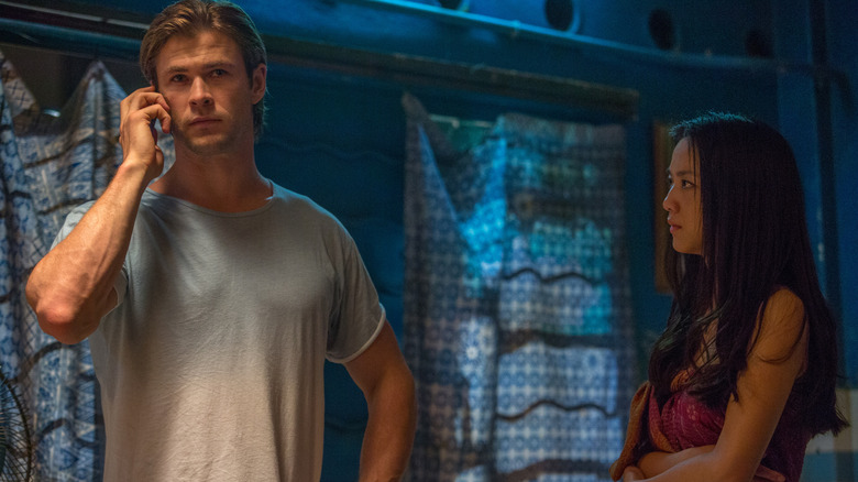 Nicholas Hathaway talking on the phone in a white t-shirt while Chen Lien looks on.