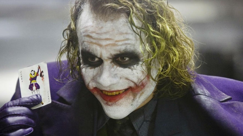 The Dark Knight, Heath Ledger as the Joker smiling and holding his card