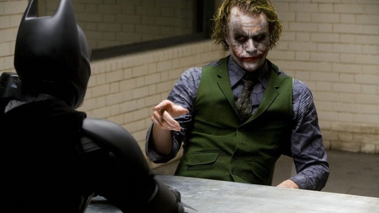 The Joker sitting opposite Batman and pointing at him in The Dark Knight