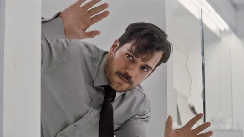 Henry Cavill as August Walker emerges from a bathroom stall with his hands up in Mission: Impossible — Fallout