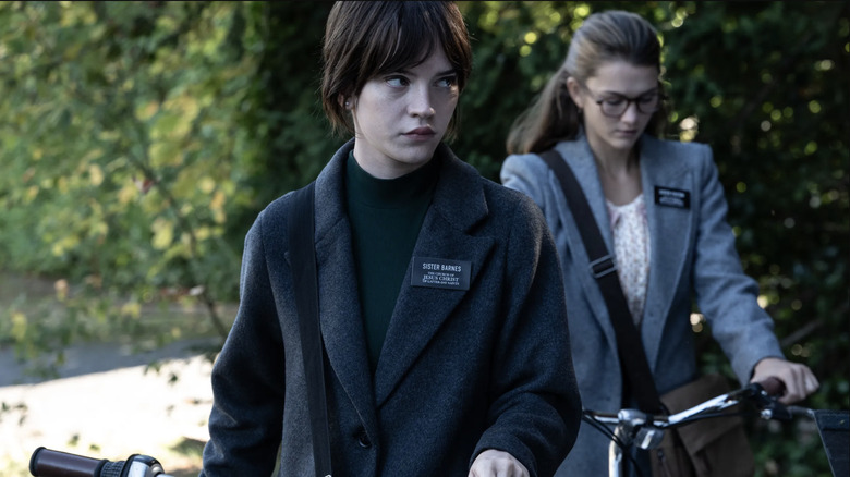 Sophie Thatcher as Sister Barnes and Chloe East as Sister Paxton walking their bikes in Heretic