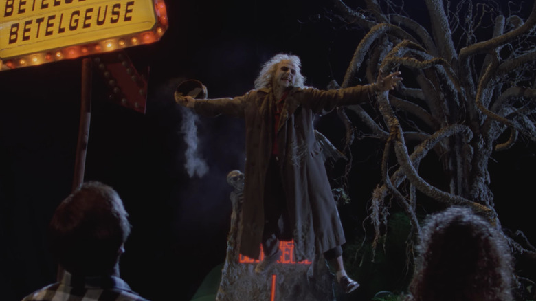 Michael Keaton as Beetlejuice floating above Alex Baldwin and Geena Davis.