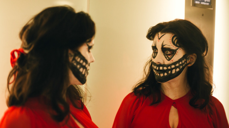 Alice Lowe as Ruth face paint in "Prevenge," dressed in red with white, black and red Halloween facepaint.