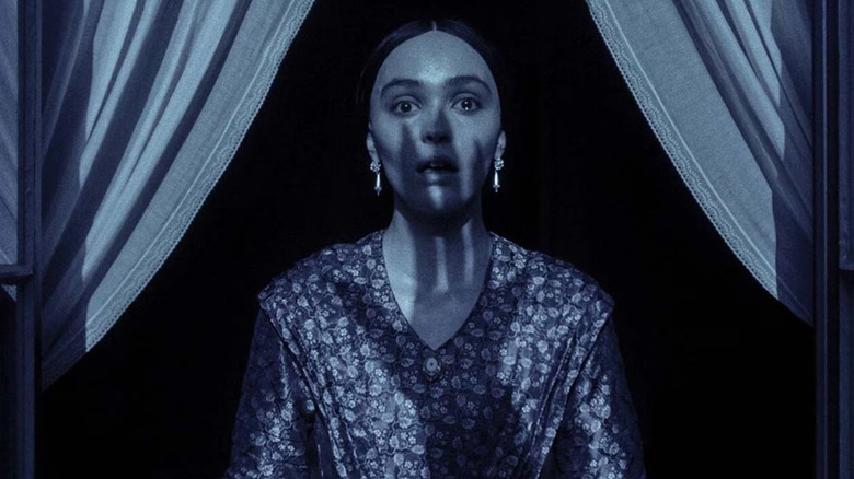 Lily-Rose Depp looks scared as the shadow of a hand appears in Nosferatu