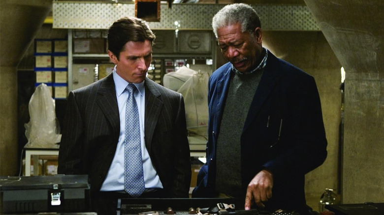 Christian Bale's Bruce Wayne consults with Morgan Freeman's Lucius Fox in a lab in Batman Begins