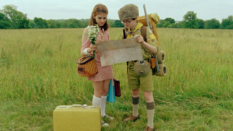 Suzy de Kara Hayward e Sam de Jared Gilman lendo o mapa em um campo no Moonrise Kingdom