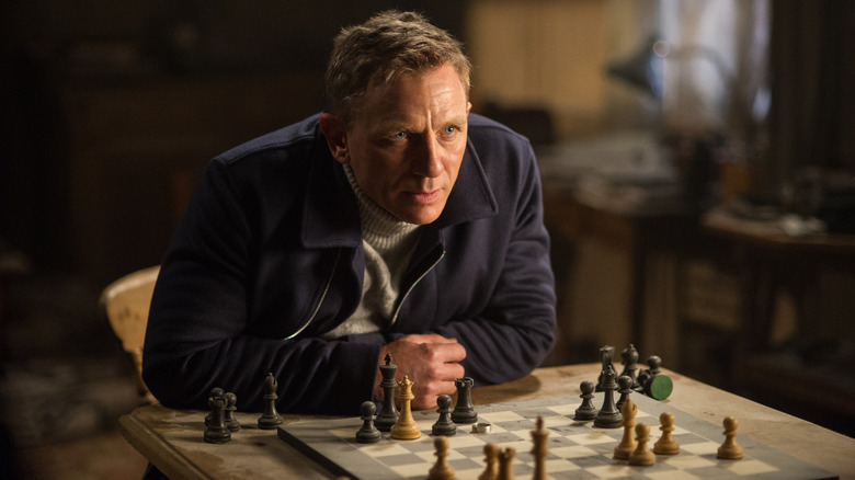 Daniel Craig como James Bond, encostado em um quadro de xadrez em Specter