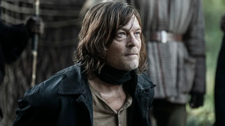 Daryl Dixon de Norman Reedus se sienta en el suelo con las manos detrás de la espalda y el bozal alrededor del cuello, en The Walking Dead: Daryl Dixon