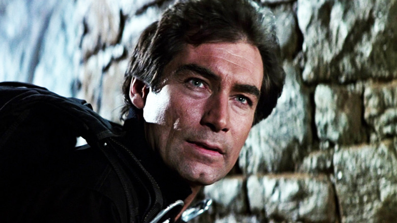 Timothy Dalton's James Bond stands by some rocks in The Living Daylights