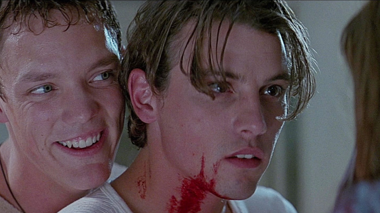 Matthew Lillard as Stu Macher smiles standing behind a bloody Skeet Ulrich as Billy Loomis in Scream (1996)