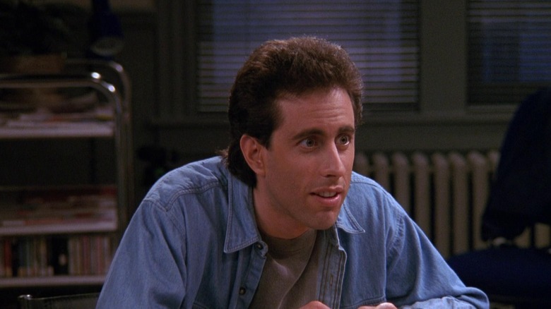 Jerry Seinfeld in a blue shirt in his apartment.