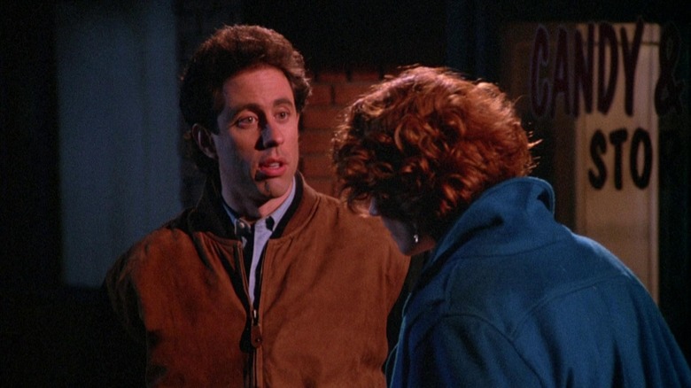 Jerry Seinfeld, outdoors in an alley, talking to someone up close.