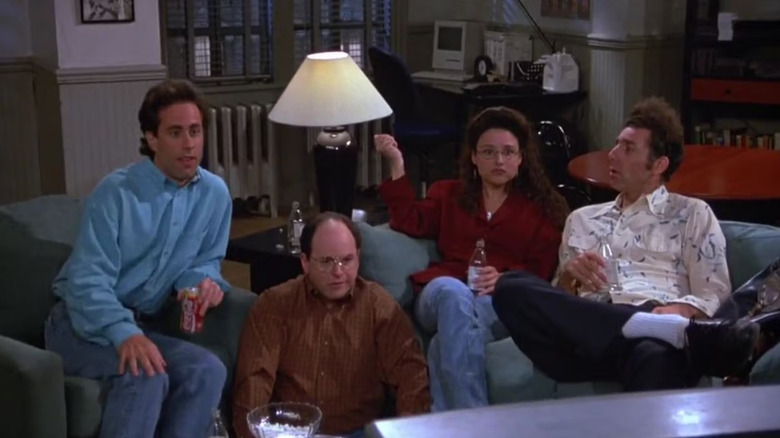 Jerry Seinfeld as Jerry, Jason Alexander as George, Julia Louis-Dreyfus as Elaine, and Michael Richards as Kramer watching TV on Seinfeld