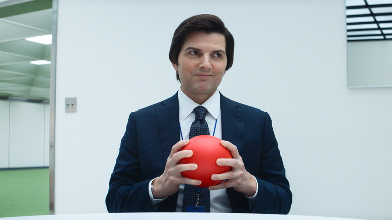 Mark smiling in the MDR office while holding a red ball in Severance