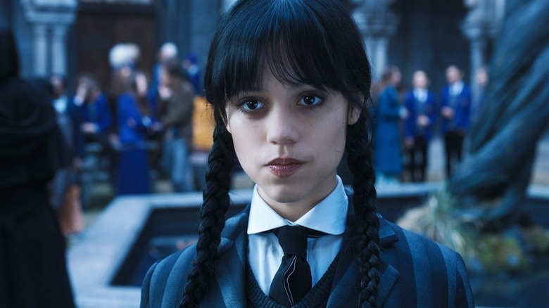 Wednesday Addams olhando para a escola de uniforme