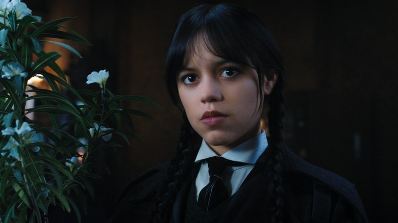 Wednesday Addams olhando para o uniforme escolar de folhagem