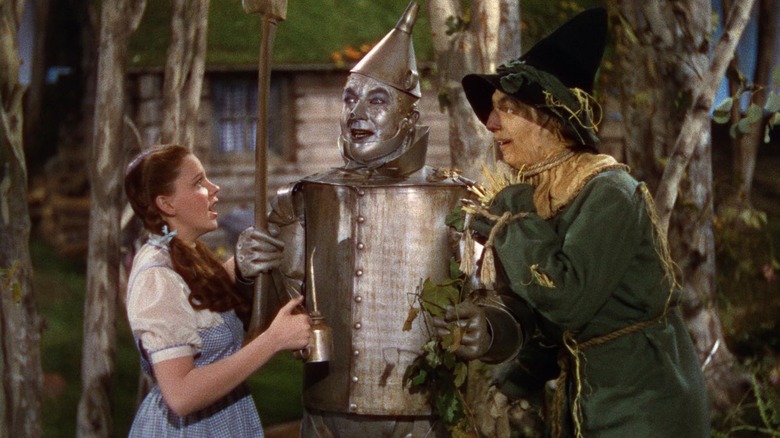 Dorothy giving the Tin Man some oil with Scarecrow looking on in The Wizard of Oz