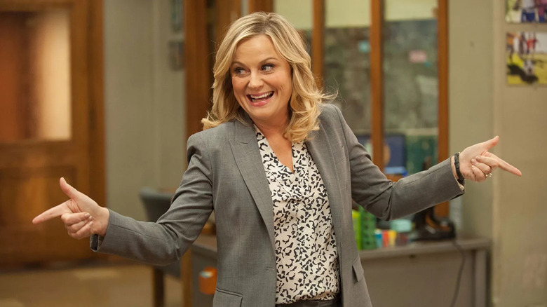 Leslie Knope doing finger guns and smiling in the office on Parks and Recreation