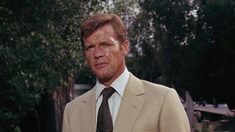 Roger Moore's James Bond stands in a tan suit against a green background in Live and Let Die