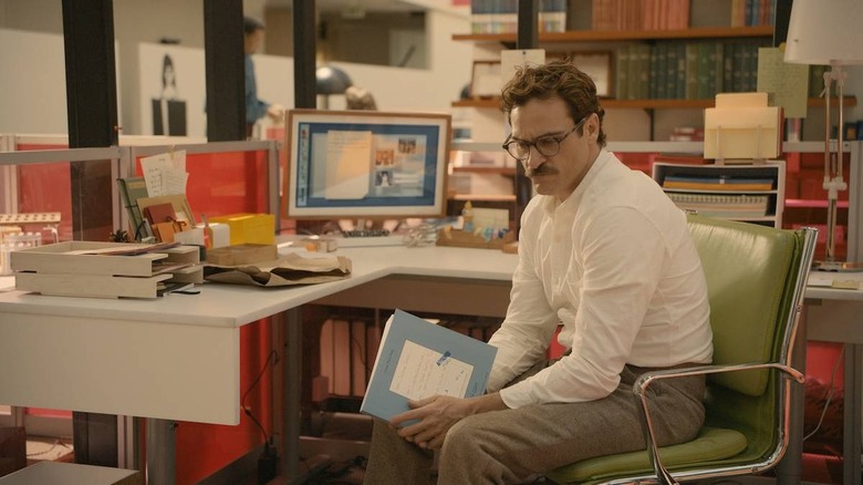 Joaquin Phoenix sitting at his desk in Her