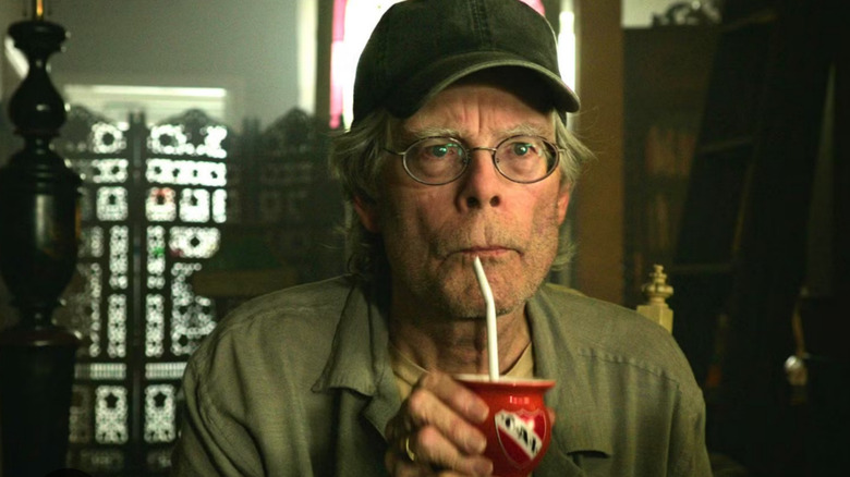 It: Chapter Two, Stephen King drinks through a straw behind the counter of a shop