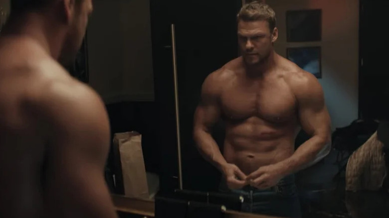 Alan Ritchson's Jack Reacher looks in the mirror as he stands shirtless in Reacher