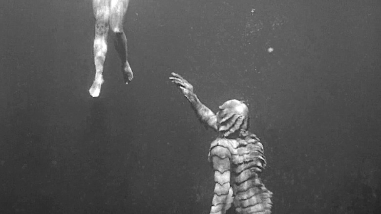 The Creature reaches out to Julia Adams' legs in Creature from the Black Lagoon