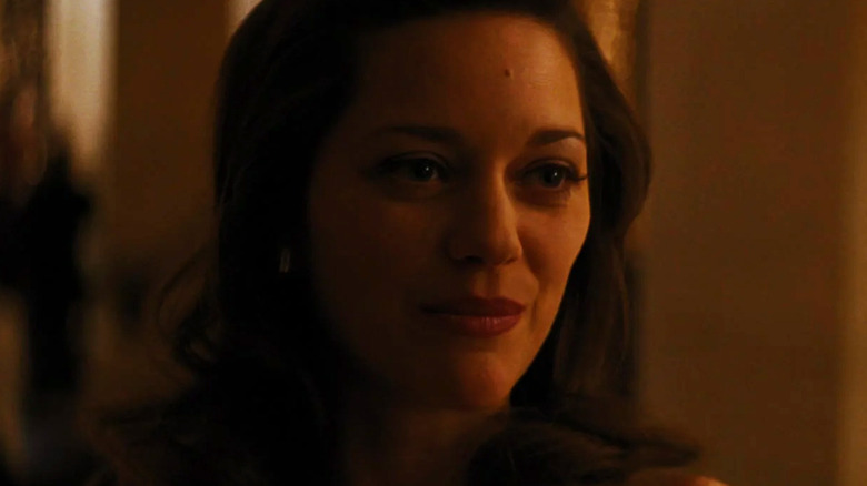 Marion Cotillard's Miranda Tate/Talia Al Ghul smiles while lit by a warm light in The Dark Knight Rises