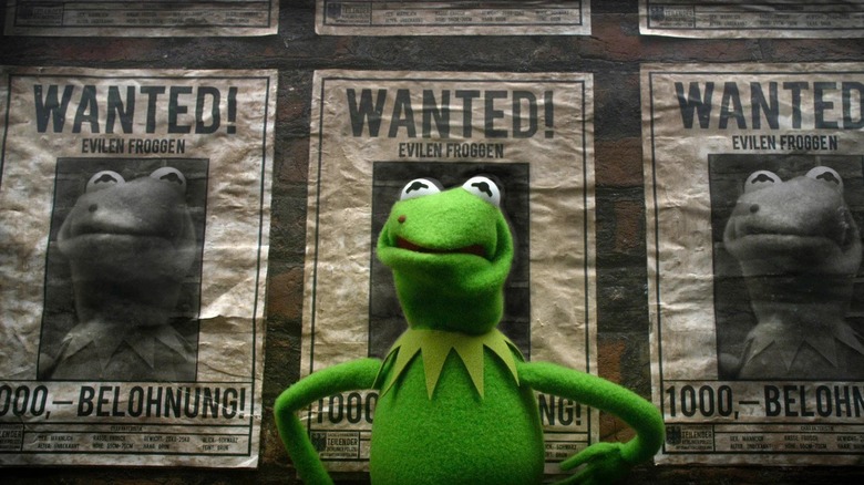 Kermit the Frog stands in front of a wall with 