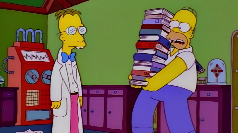 Homer, carregando uma grande pilha de livros, conversando com o professor Frink em um laboratório. Dos Simpsons.